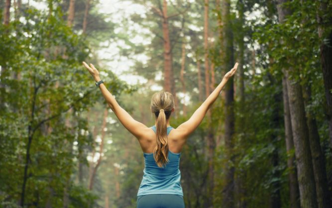 Woman standing in nature with arms outstretched